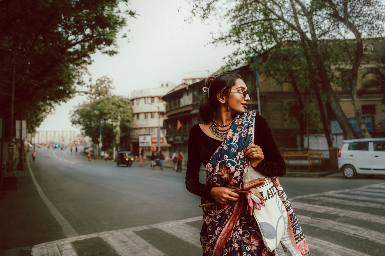 Fashionable woman in traditional Indian saree posing on a city street in Pune, India.